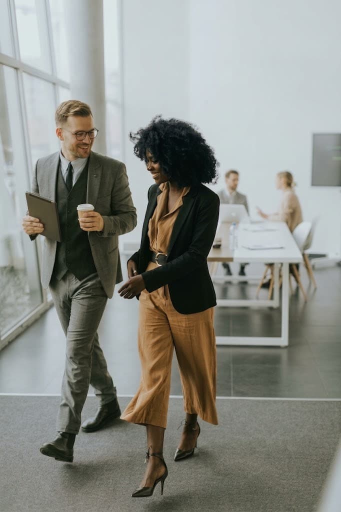 Two colleagues walking and talking in a bright office